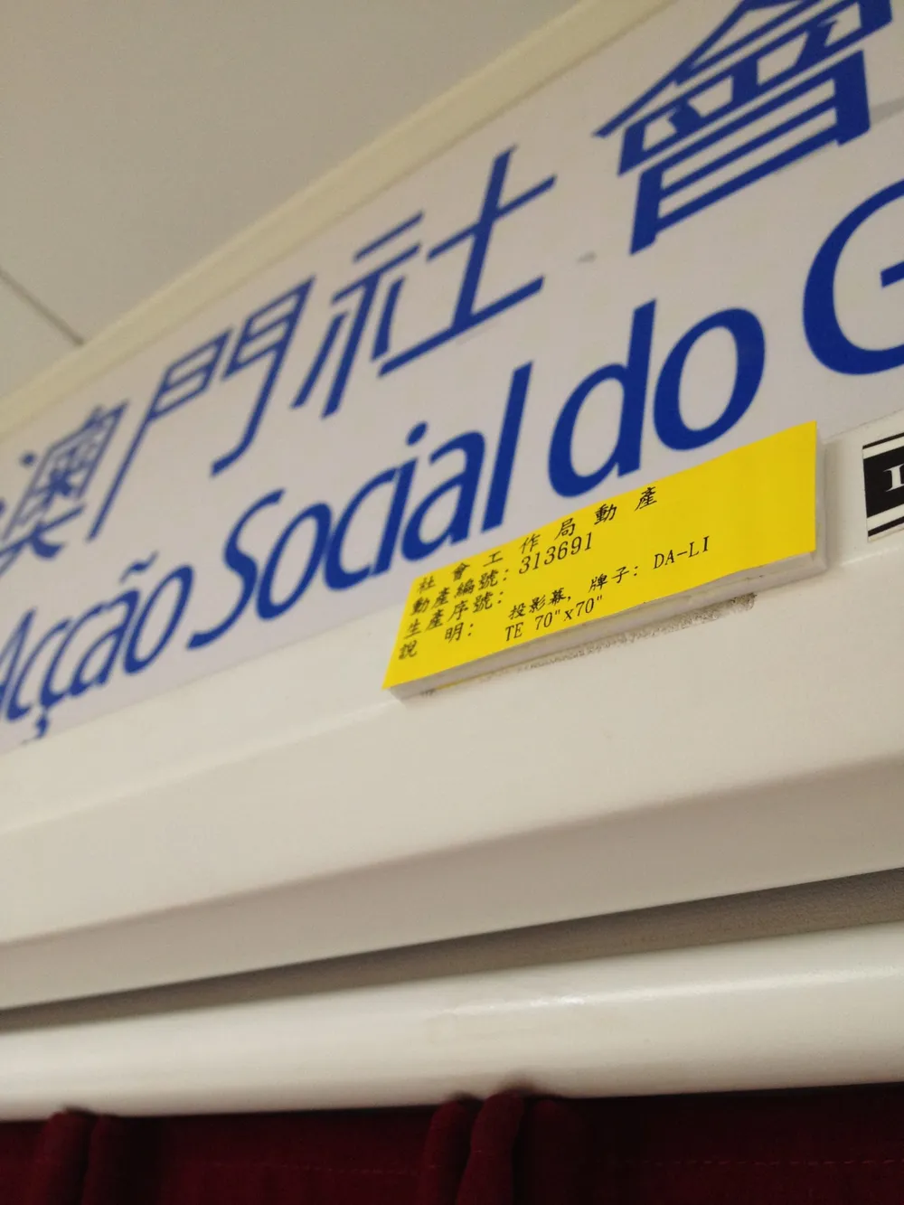Yellow printed asset tag with an asset number stuck on office equipment