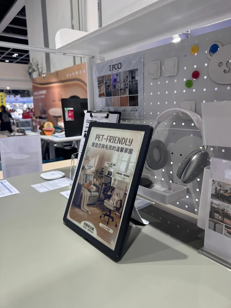 Colour ePaper sign showing a pet-friendly furniture promotion on a desk at an exhibition booth