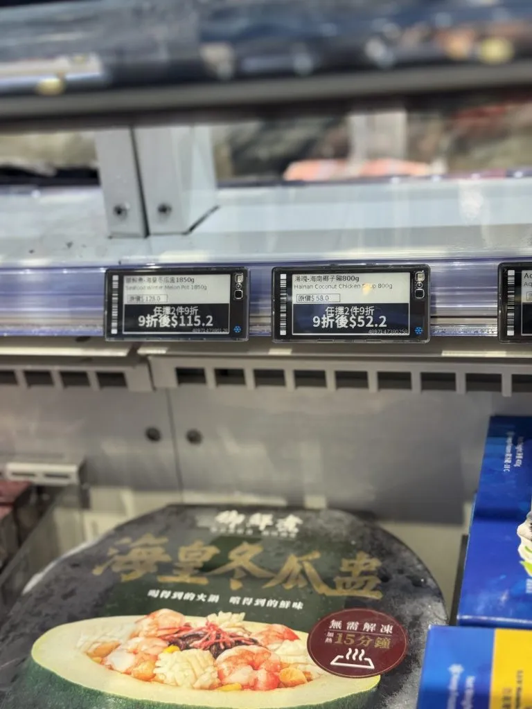 Electronic shelf labels on a freezer rail showing buy-two discount prices for frozen seafood dishes