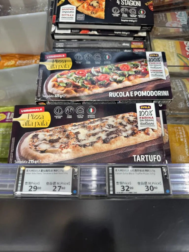 Electronic shelf labels showing regular and member prices for frozen Italian pizzas