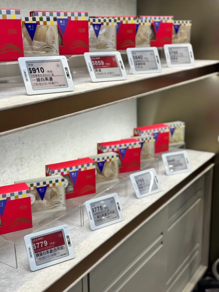 Red-and-white and black-and-white electronic shelf labels on display shelves of boxed bird's nest