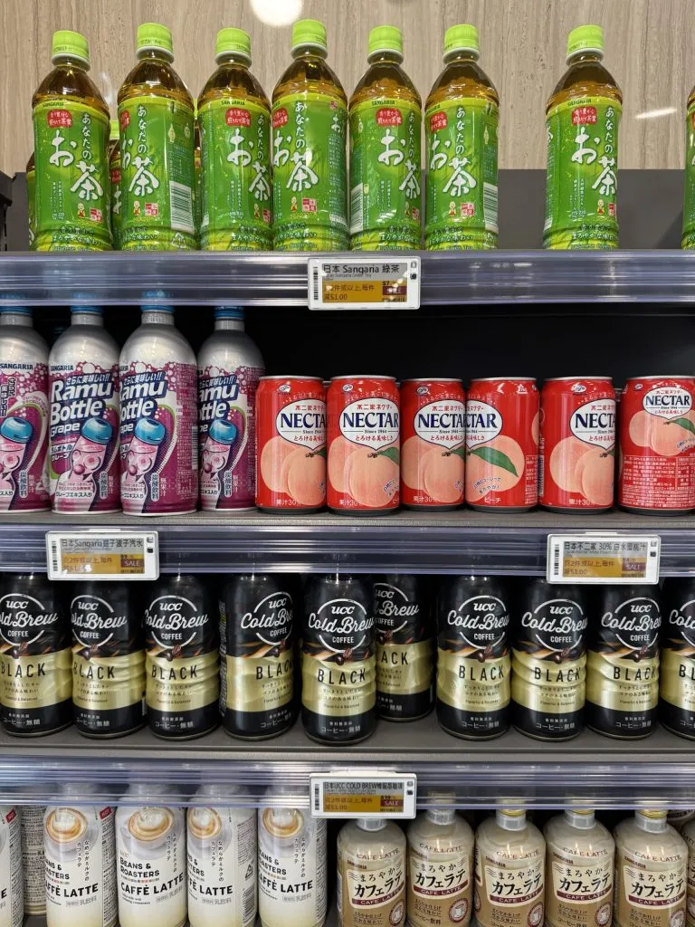 Electronic shelf labels with yellow sale panels on a drinks chiller of Japanese tea, juice and canned coffee